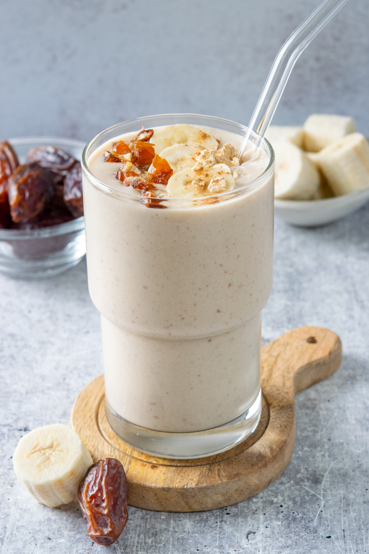 Homemade banana data smoothie garnished with chopped medjool dates, banana slices, oats and cinnamon.