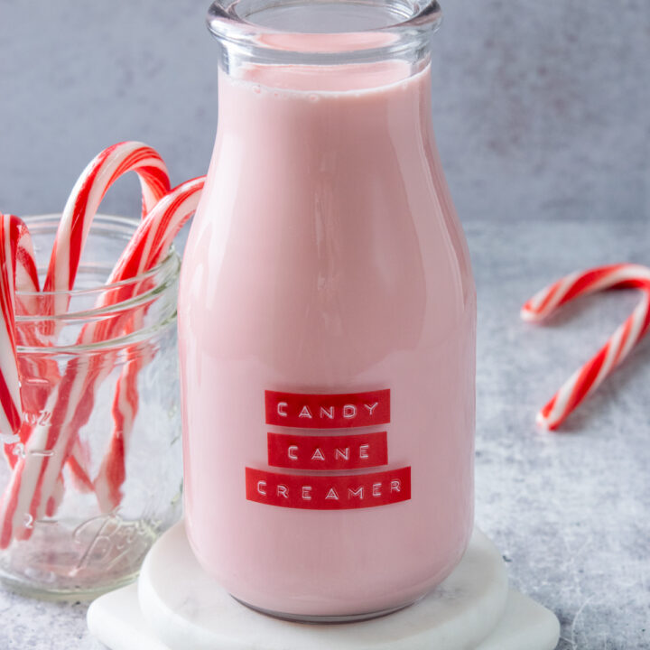 Homemade candy cane coffee creamer in a bottle next to a jar filled with candy canes.