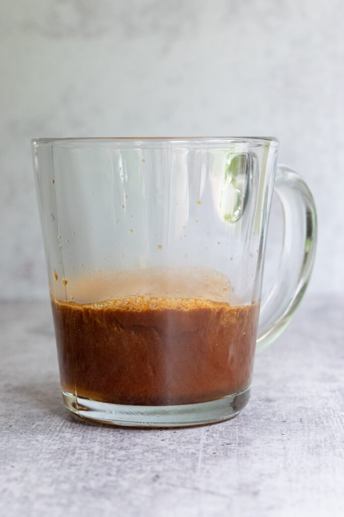 Espresso added to cookie butter syrup in a mug to make a cookie butter latte.