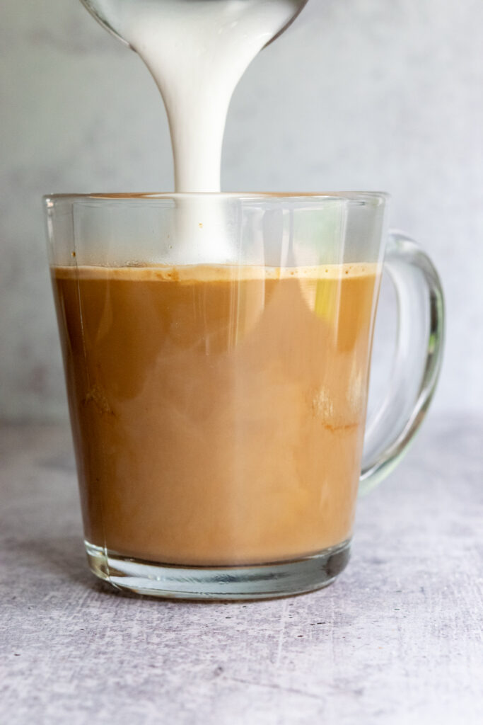 Topping a cookie butter latte with foam from the steamed milk.