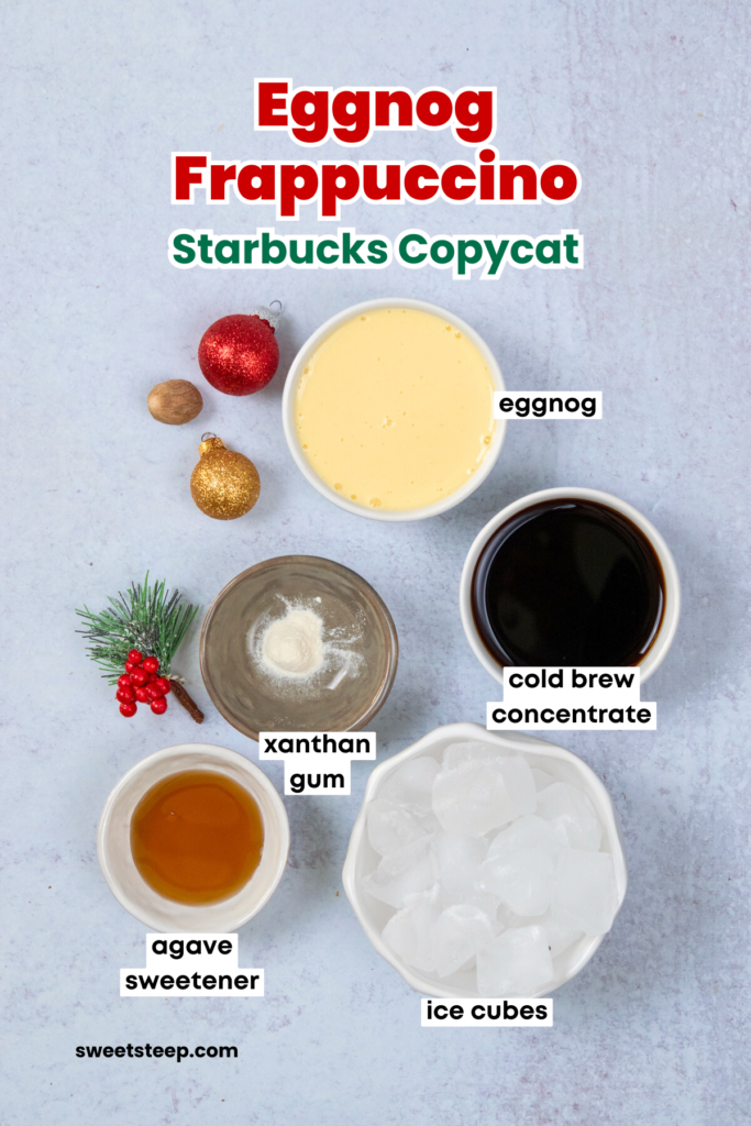 All the ingredients needed to make an eggnog frappuccino like Starbucks at home. There's a bowl with eggnog, a bowl with cold brew concentrate, ice cubes, xanthan gum, and agave sweetener. The image has text overlay that reads. "Eggnog Frappuccino. Starbucks Copycat."