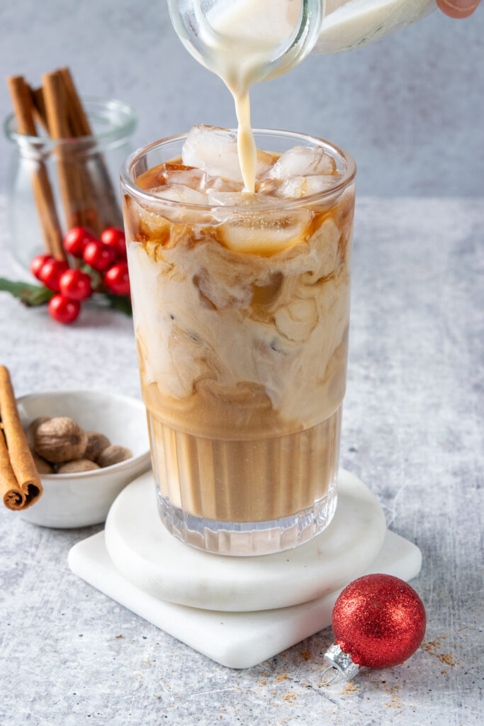 Pouring eggnog creamer into an iced coffee drink.