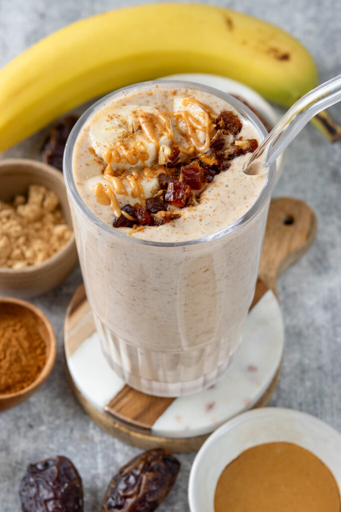 A top-down picture of the most indulgent looking date smoothie with sliced banana, chopped dates and peanute butter drizzled on top.