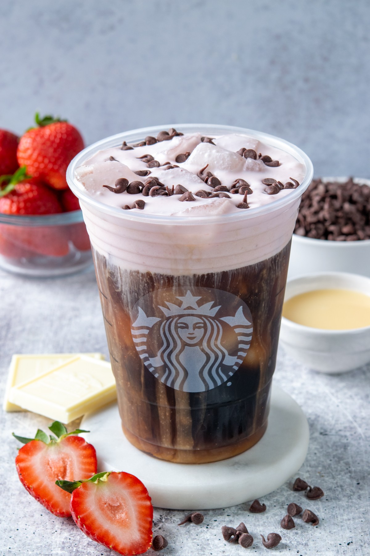 Homemade white chocolate strawberry cream cold brew Starbucks copycat garnished with mini chocolate chips and fresh strawberries.